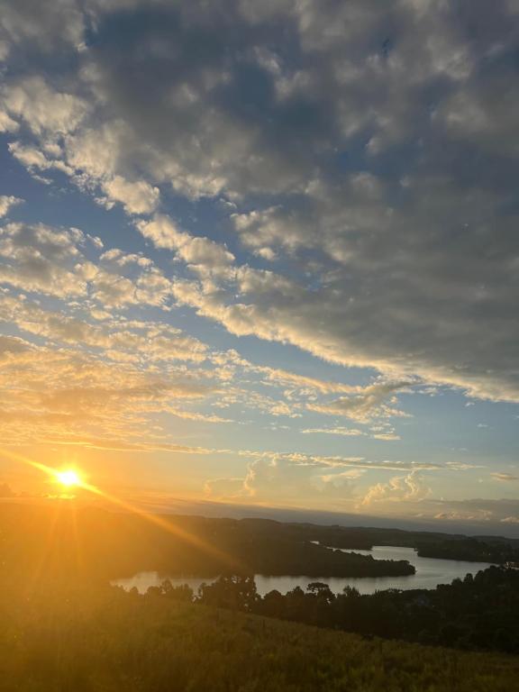 a sunset over a river with the sun in the sky at Galpão, Pousada Paraíso do Arruda in Lages