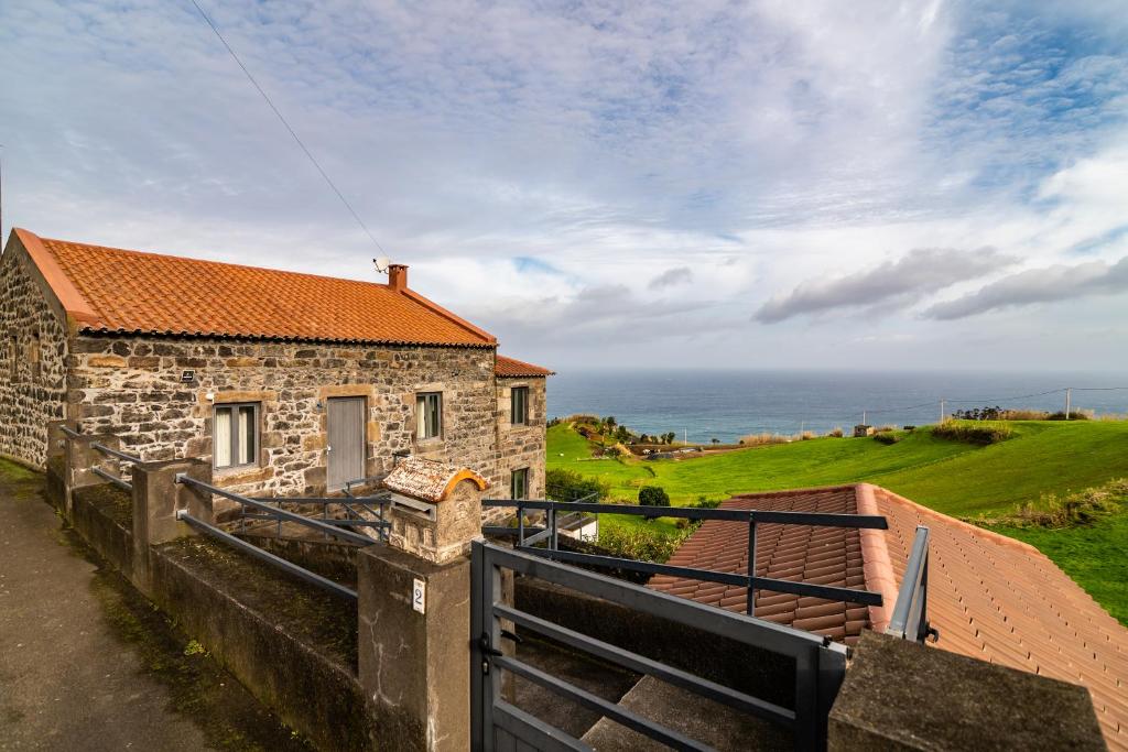 a stone house with a view of the ocean at Casa Miradouro do Pesqueiro in Feteira Grande