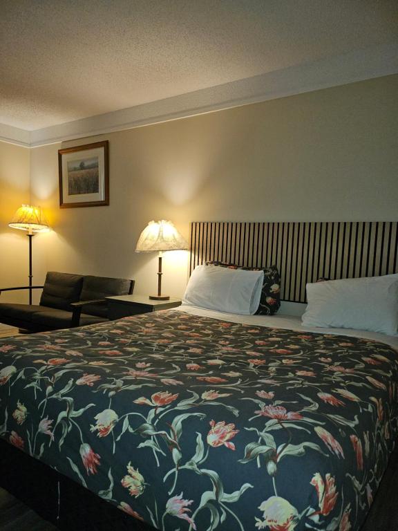 a bedroom with a large bed with a floral blanket at Moosomin Country Squire Inn in Moosomin