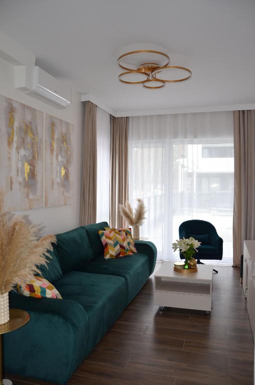 a living room with a green couch in front of a window at Apartament Eleven Międzyzdroje in Międzyzdroje