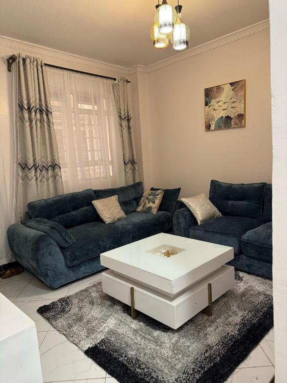 a living room with blue couches and a white table at Luxx Homes #Unit B in Ruiru