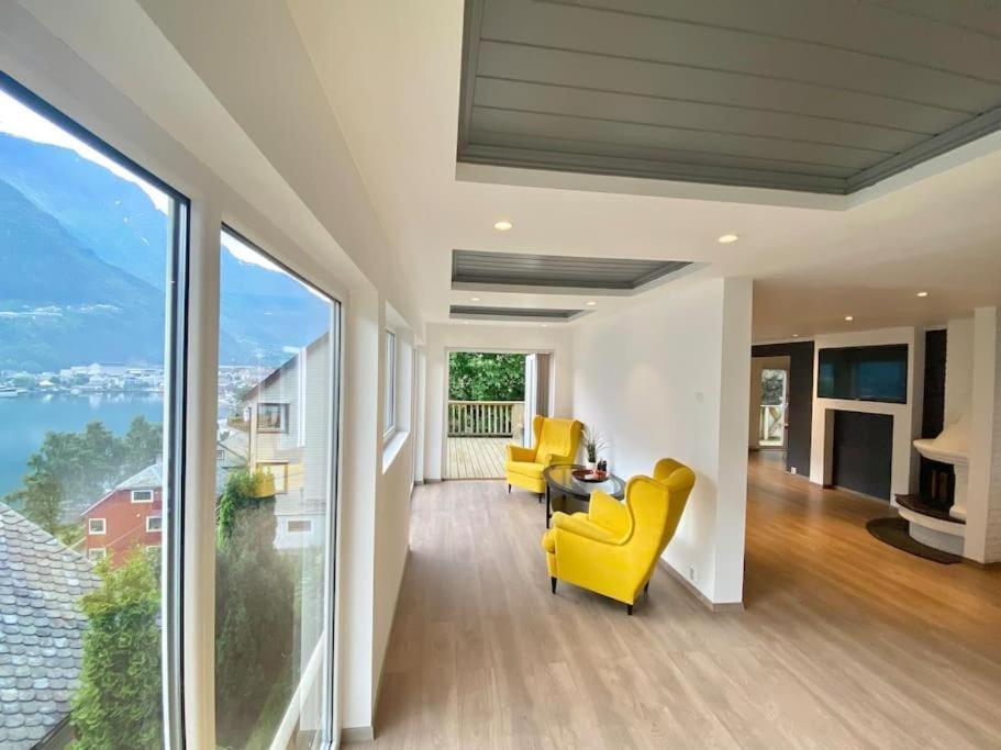 a living room with yellow chairs and large windows at Trolltunga Fjordview House, Odda in Odda