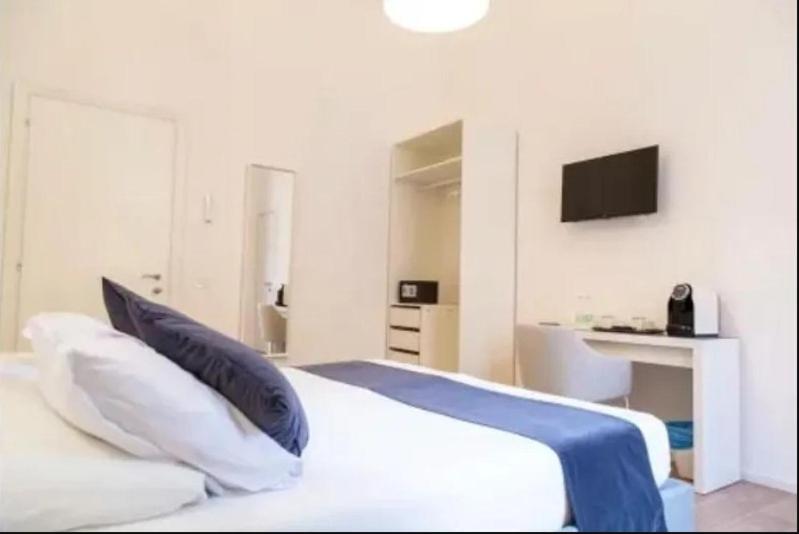 a bedroom with a white bed with a tv on the wall at Urban Stay Siena in Siena