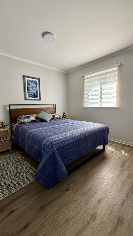 a bedroom with a bed with a blue comforter and a window at Green House, by Pewma Apart Hotel in Diguillín