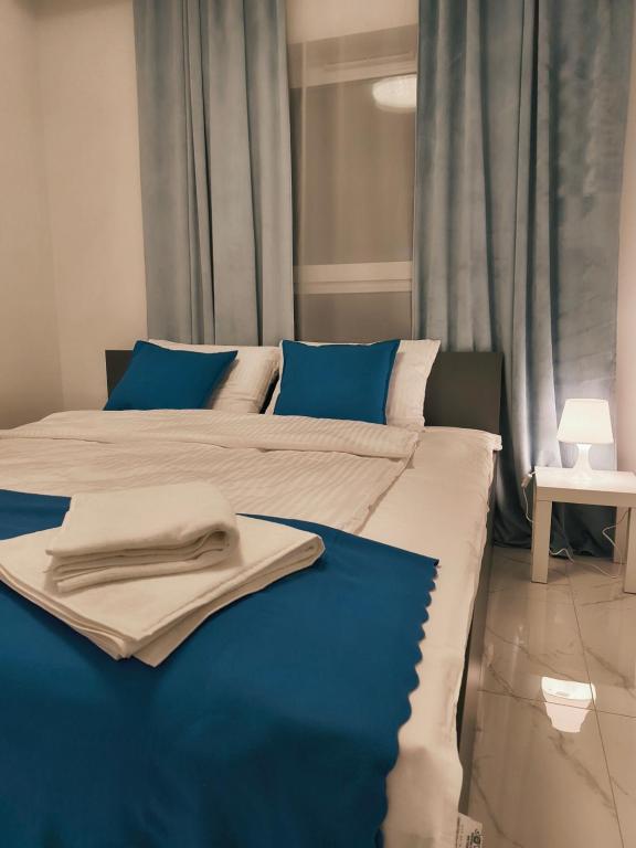 a large bed with blue and white sheets and blue pillows at Aura Apartamenty 3 in Brzeg