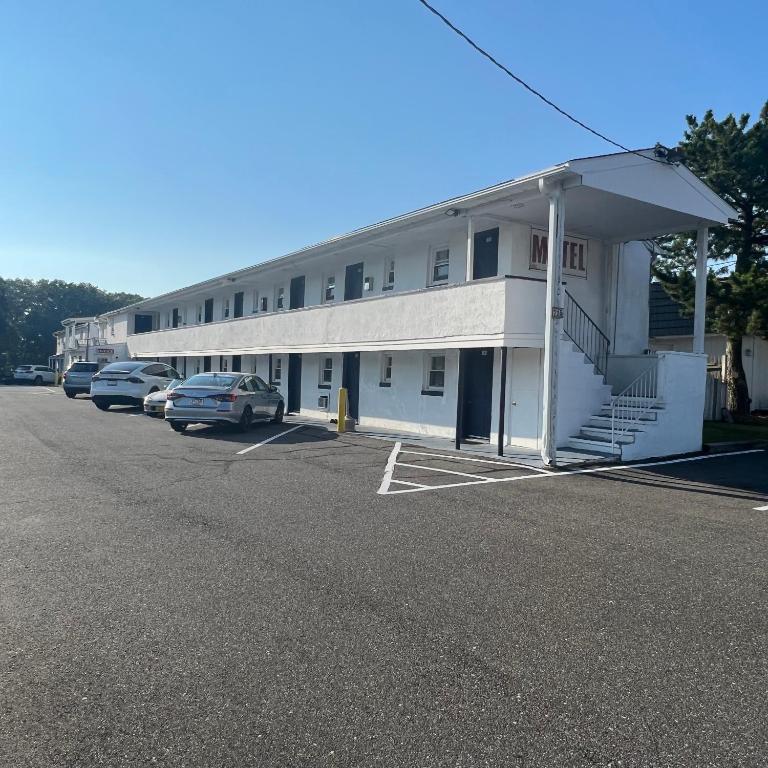 a large white building with cars parked in a parking lot at Budget Inn in Somers Point
