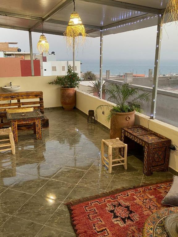 a patio with tables and benches and a view of the ocean at Breeze surf lodge in Tamraght Ouzdar
