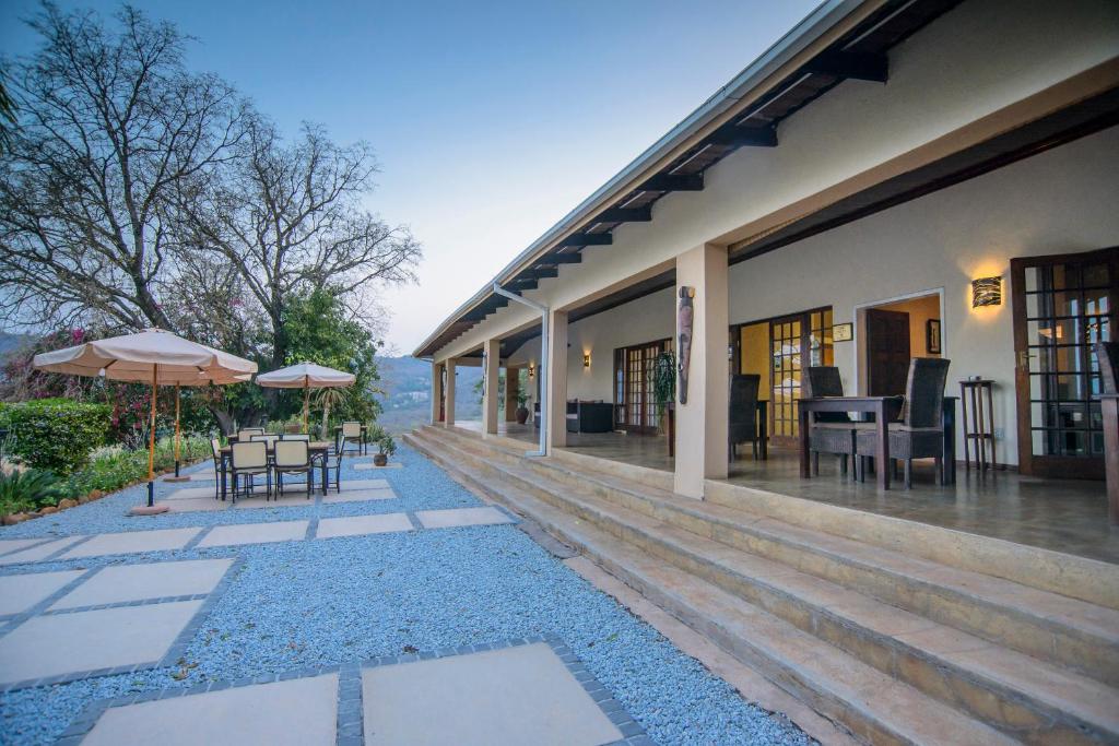 un patio esterno con tavoli e ombrelloni su un edificio di Abangane Guest Lodge a Hazyview