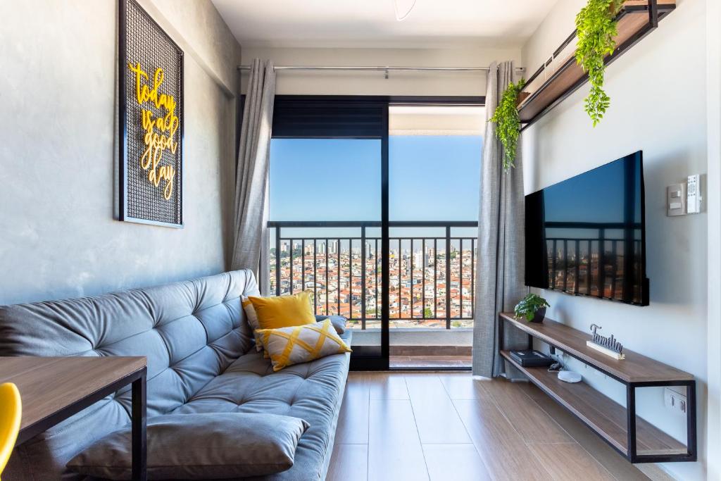 a living room with a couch and a large window at Lindo e moderno próximo ao Expo Center Norte in São Paulo
