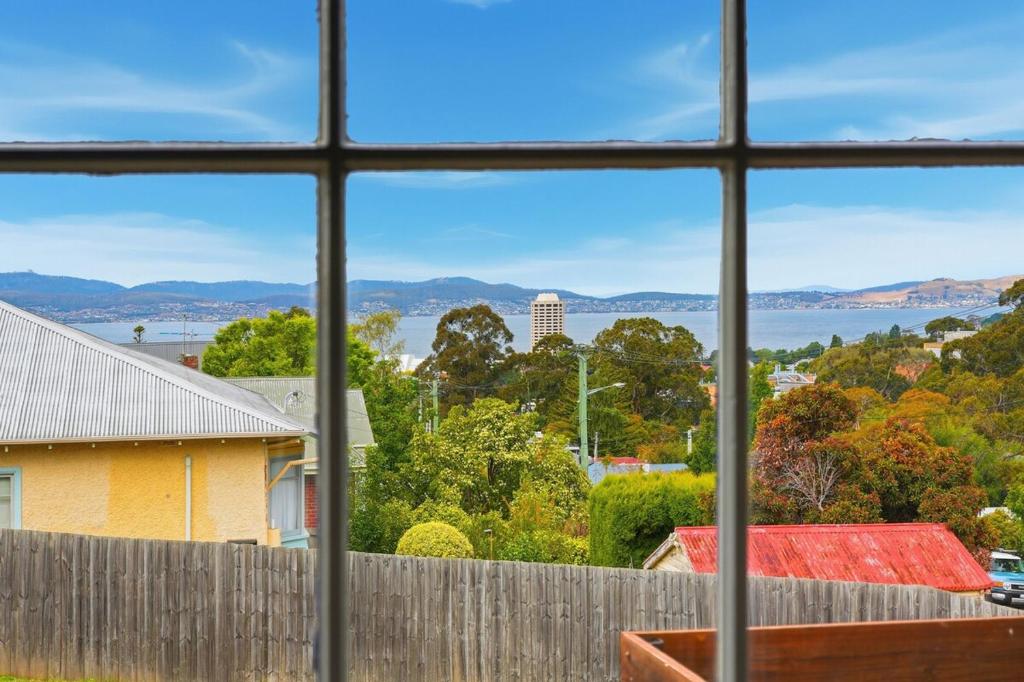 a view of the water from a house window at Charming Sandy Bay Stay in Sandy Bay