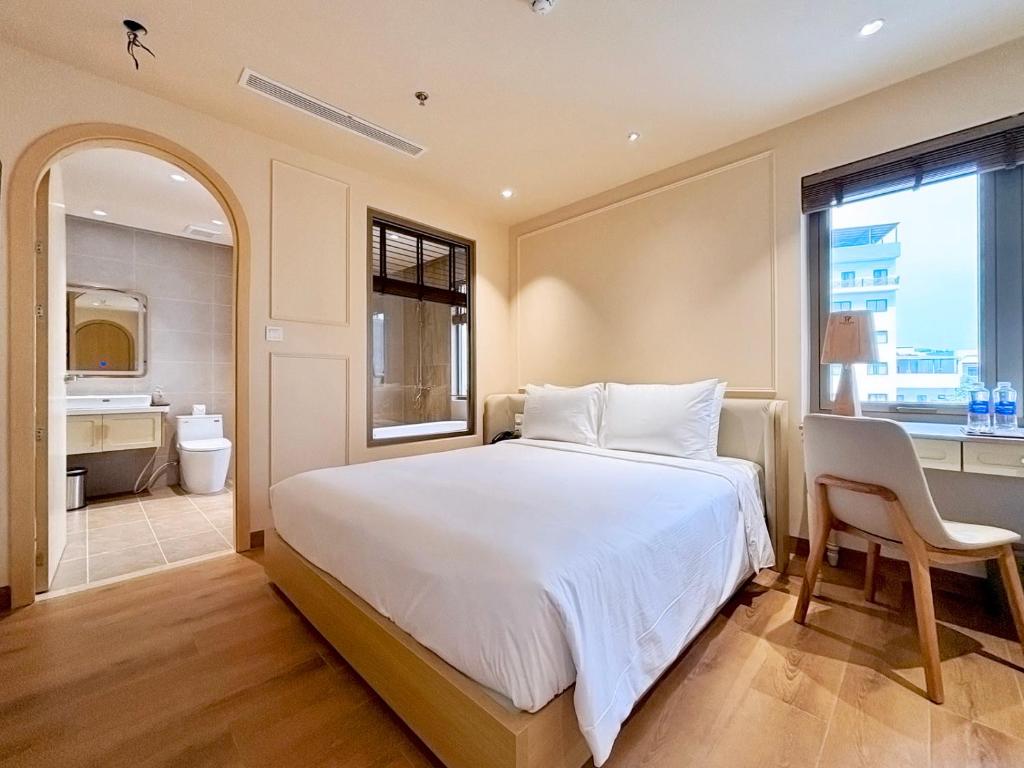 a bedroom with a large white bed and a bathroom at Peace Home Boutique Hotel in Phan Thiet