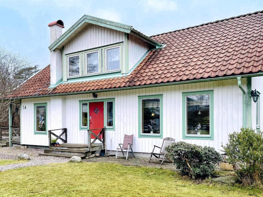 a white house with a red door and two chairs at 4 star holiday home in ONSALA-By Traum in Onsala