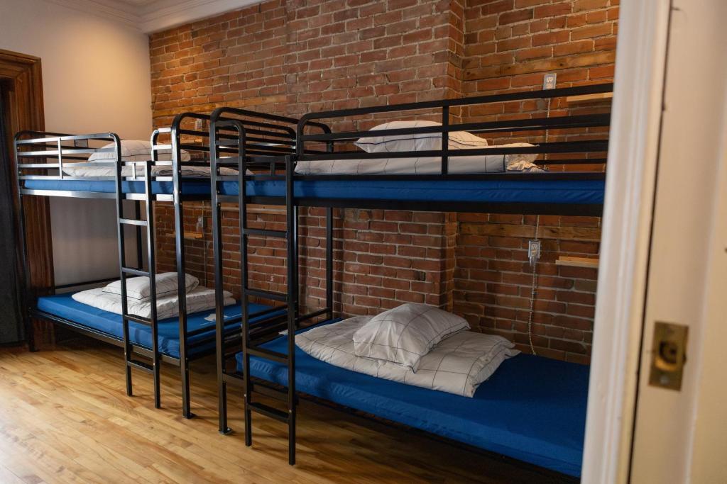 two bunk beds in a room with a brick wall at Auberge Le Treehouse in Montreal