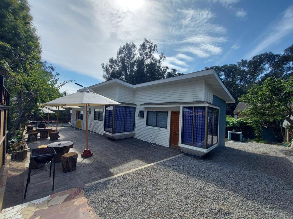 a white house with an umbrella and a patio at Cabañas Alquymia in Algarrobo