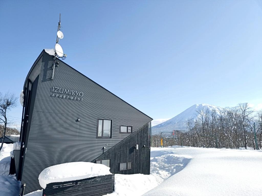 a building with a sign on it in the snow at ニセコ泉居アパートメント in Kutchan