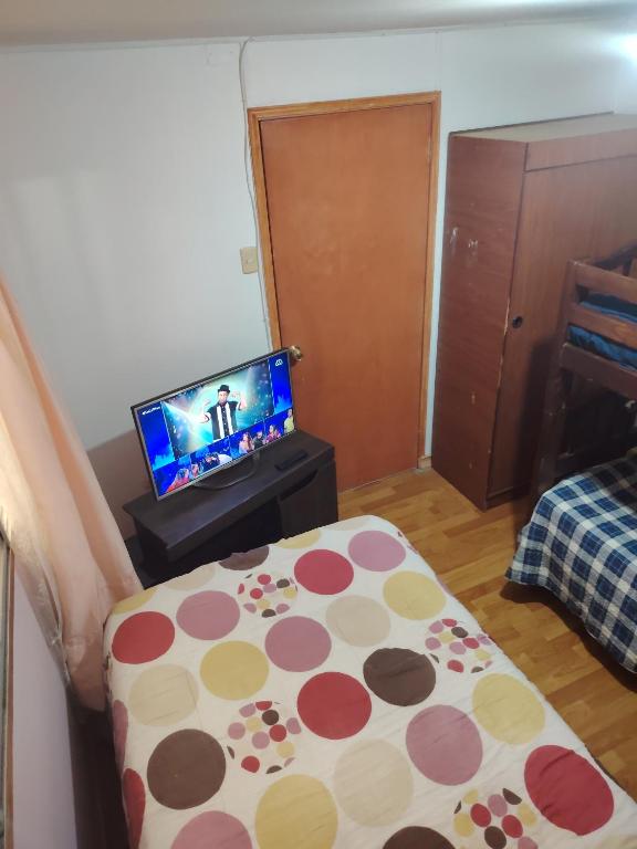 a room with a bed and a television with a table at Casa de alojados in Antofagasta
