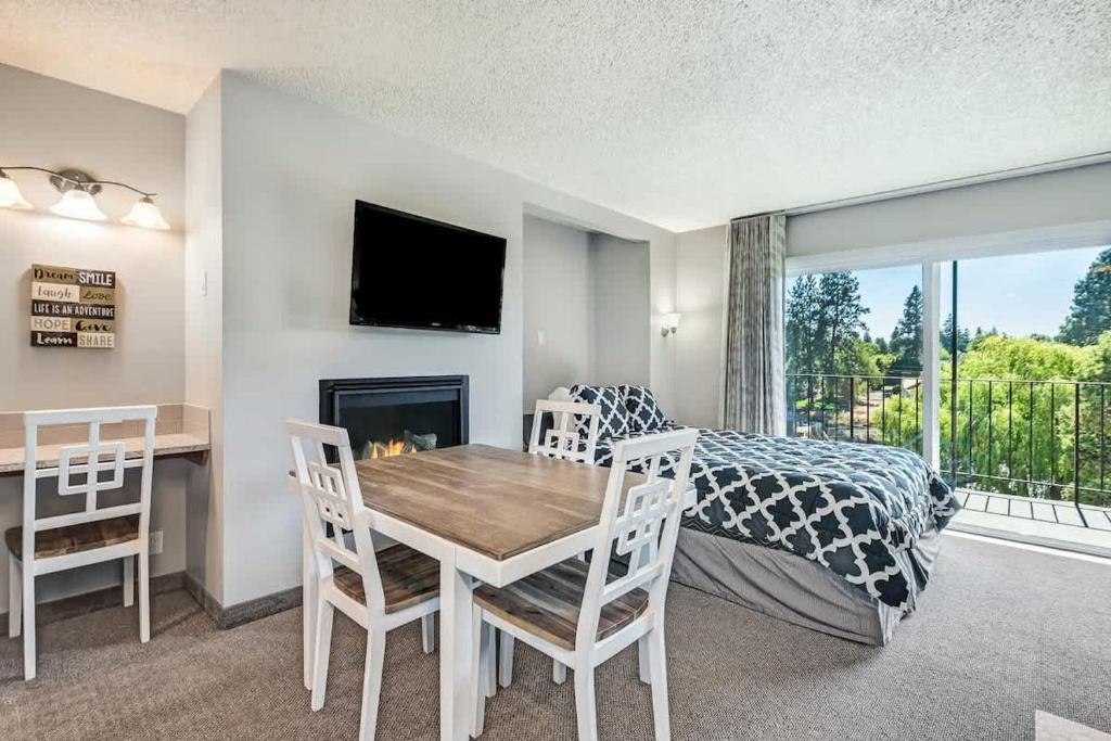 a bedroom with a bed and a table with a fireplace at Downtown Condo with Riverview & Balcony in Bend