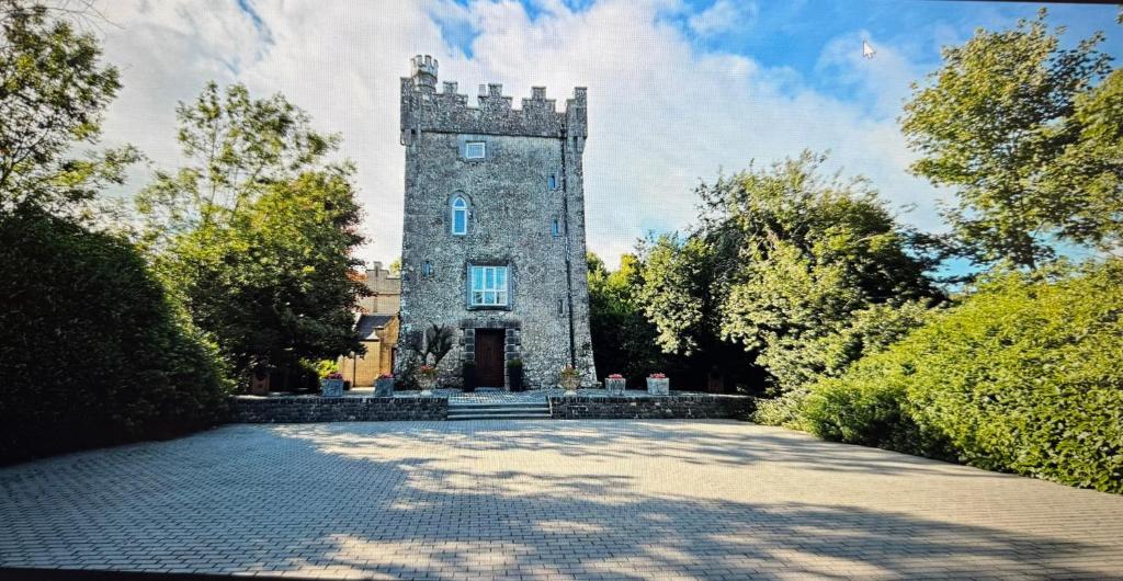 a building with a tower in the middle of a driveway at Moyvannan Castle on 7 Acres in Roscommon
