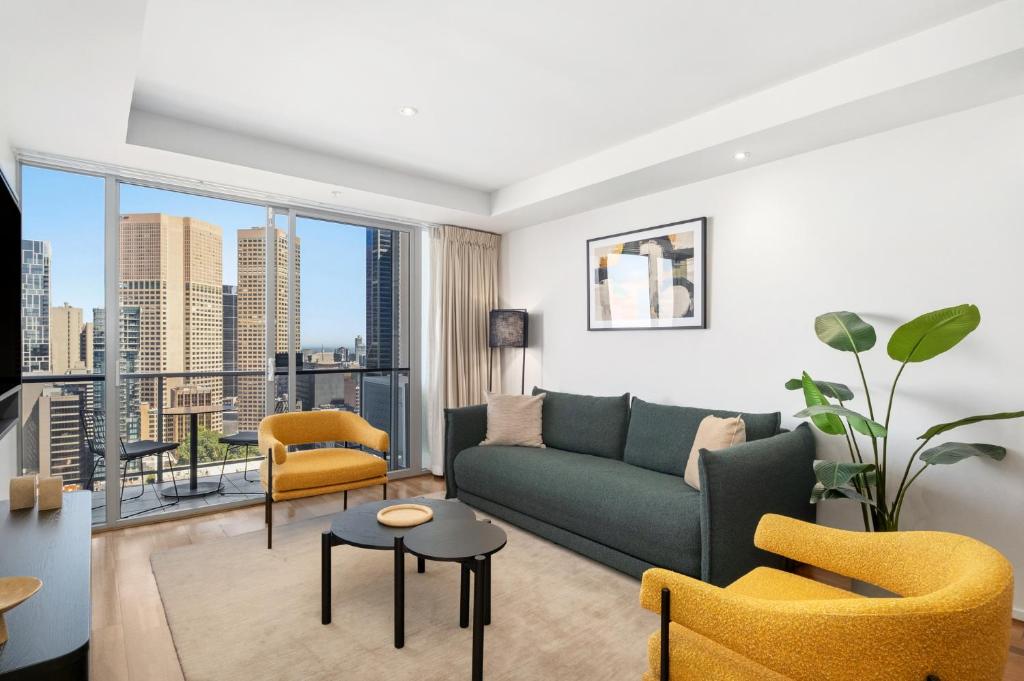 a living room with a couch and chairs and a large window at Urban Rest Melbourne in Melbourne