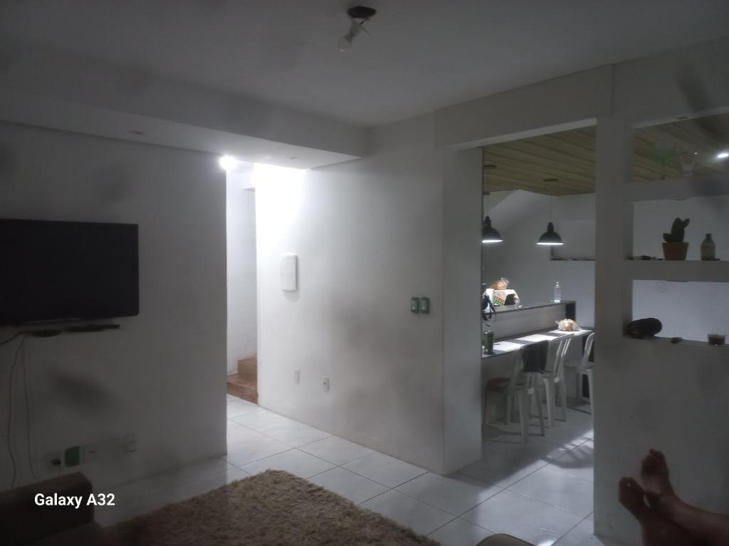 ein weißes Wohnzimmer mit Fernseher und Küche in der Unterkunft Casa do Steve in Florianópolis