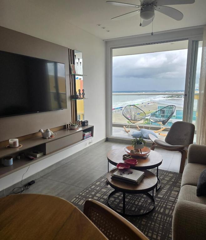 a living room with a television and a view of the beach at Luxury Oceanfront Apartment Spiaggia 2BR 3BA Playa azul Cartagena in Cartagena de Indias