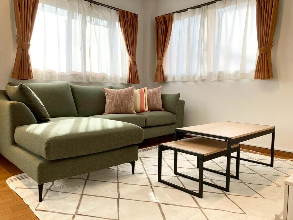 a living room with a green couch and a table at Neo Universal 05 in Wada