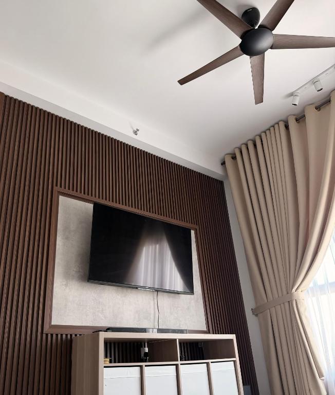 a ceiling fan and a flat screen tv on a wall at NeoSkyhigh Suites in Batu Kawan