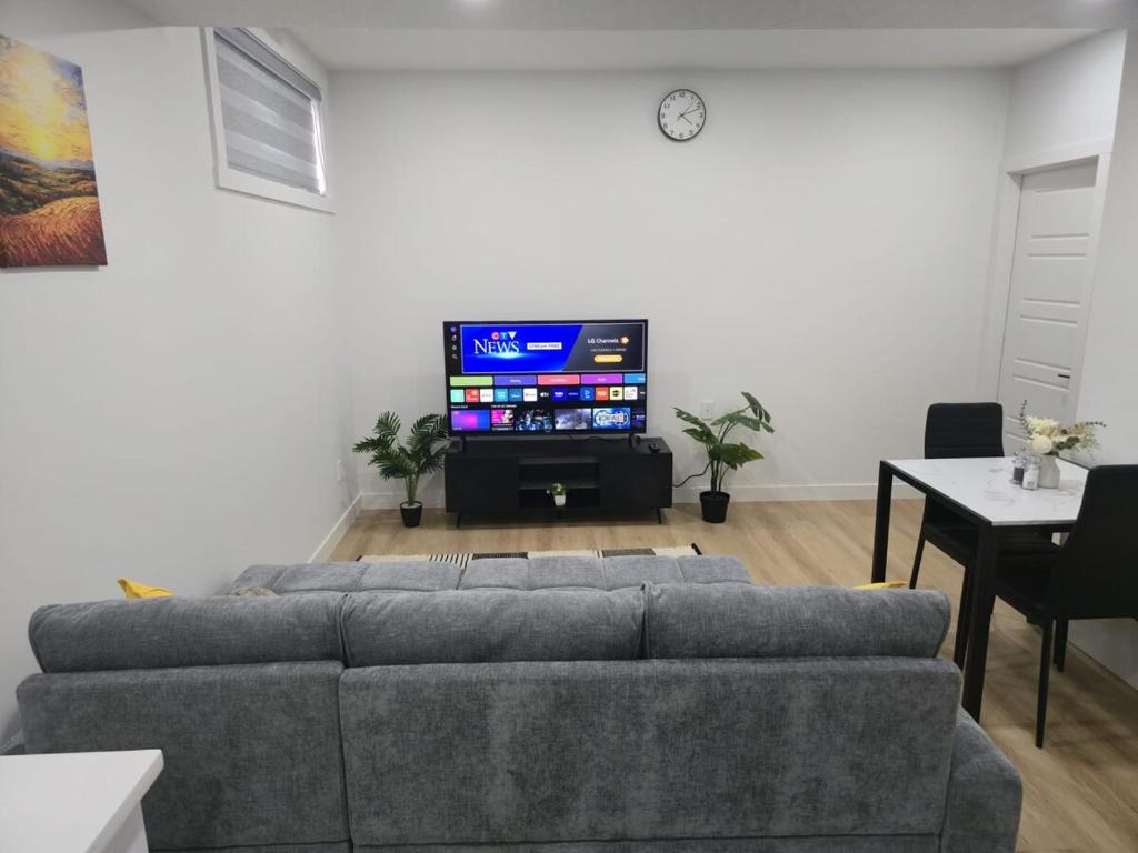 a living room with a couch and a flat screen tv at Mayfair Suite in Airdrie