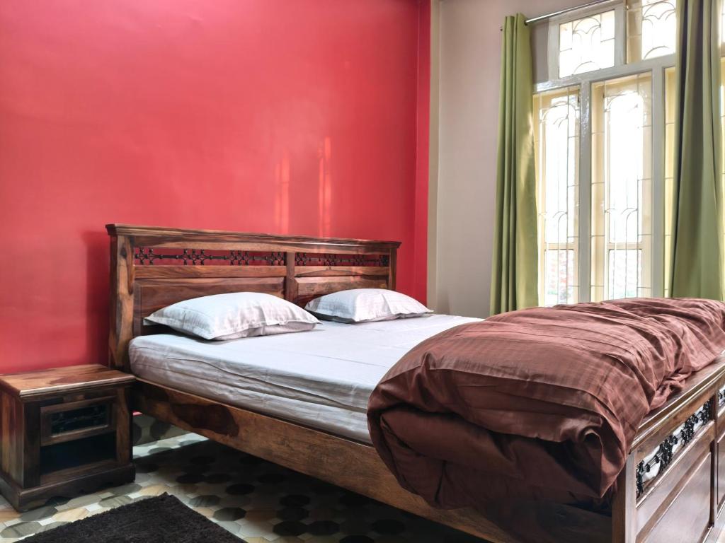 a bedroom with a bed with a red wall at Prashaanti in Guwahati