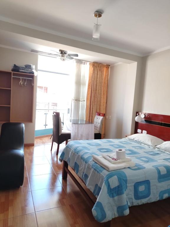 a bedroom with a bed and a chair and a window at HOSTAL REAL CERRILLOS in Moquegua