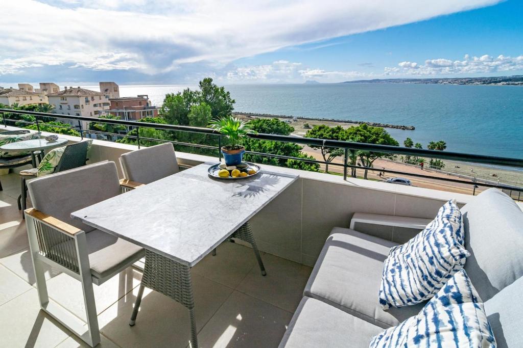 a balcony with a table and chairs and the ocean at CP - Modern Beachside Apartment in Estepona in Estepona