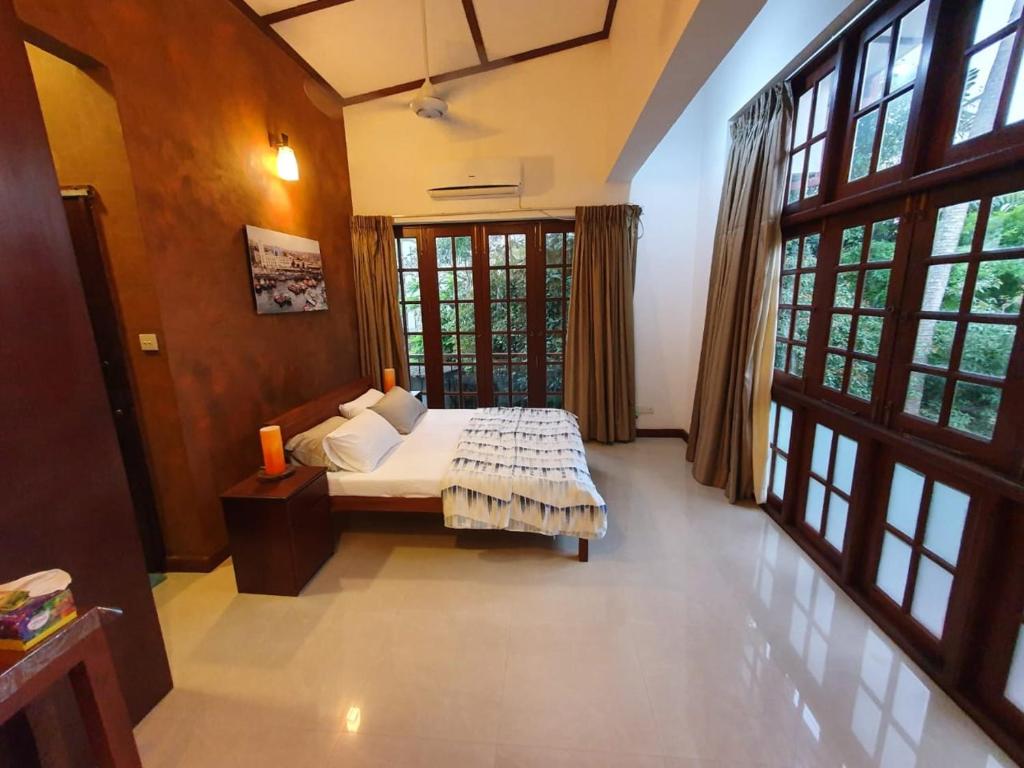 a bedroom with a bed in a room with windows at Barnes Loft Mount in Mount Lavinia