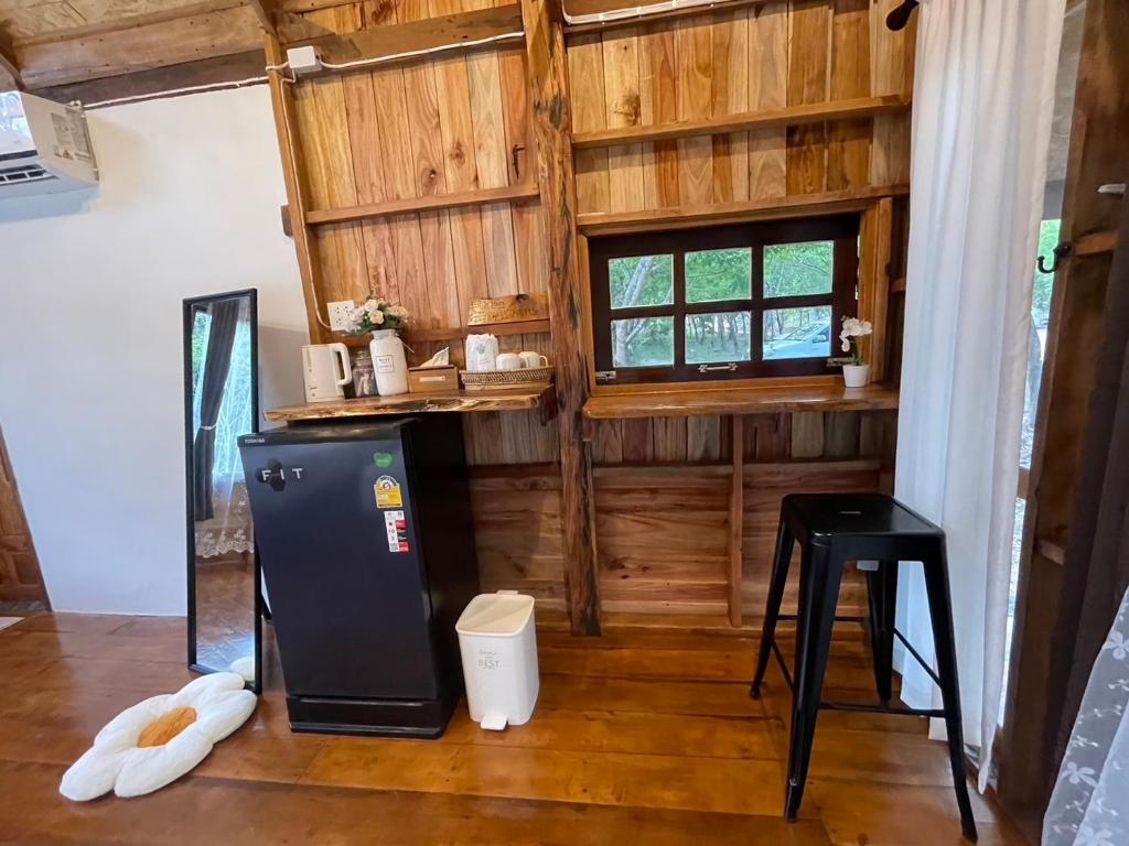 a kitchen with a refrigerator and a table and a window at Baanraipoonwana Baanwanason in Ban Nong Hu