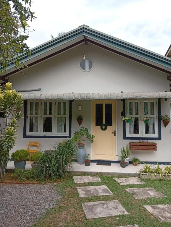 a white house with a yellow door and plants at Tiny Art House with Garden in Godagama