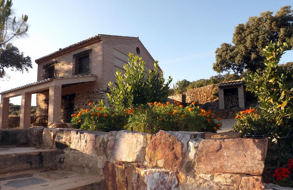 una casa con una pared de piedra y flores en apartamentos turisticos la gitanilla, en Los Navalucillos