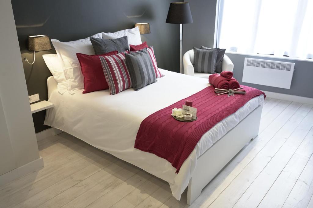 una camera da letto con un grande letto bianco con cuscini rossi e grigi di B&B BE IN BRUSSELS a Bruxelles