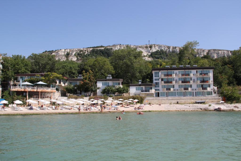 a beach with a hotel and people in the water at Hotel Oasis - Beach Access in Balchik
