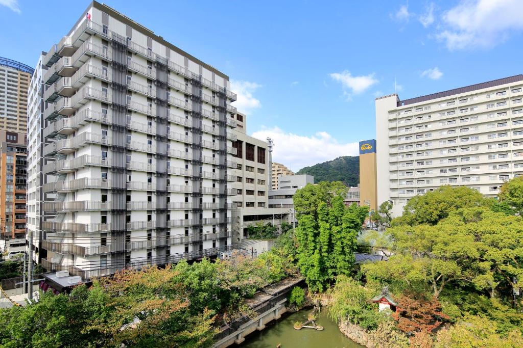 ein hohes Gebäude neben einem Fluss mit Gebäuden in der Unterkunft Hotel Monte Hermana Kobe Amalie in Kōbe