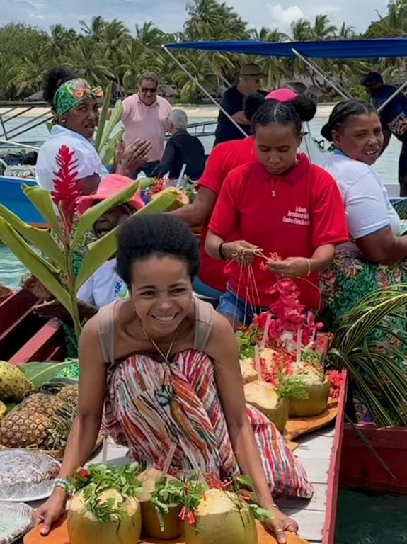 a woman sitting in front of a table with plants at Les Lodges de La Buvette ÉCO LODGE RESTAURANT in Ile aux Nattes