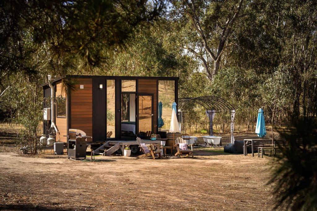 a small cabin with a table and chairs and trees at Womburra Vineyard Tiny Stay by Tiny Away in Redbank