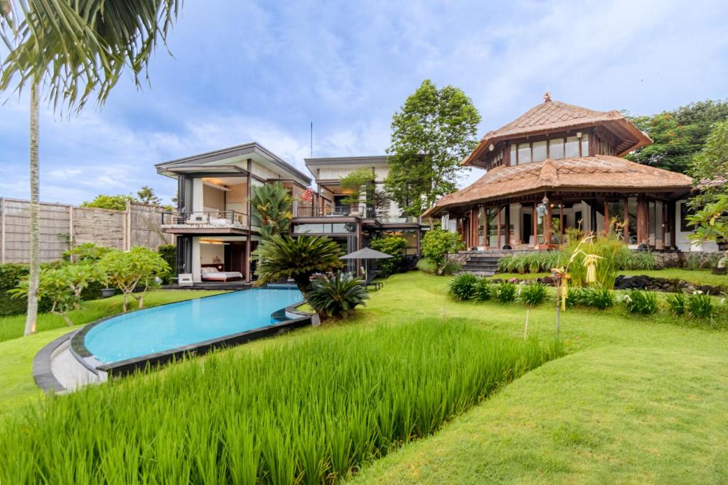 an exterior view of a house with a pool and grass at Omah Sabin Villa East in Canggu