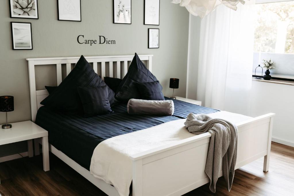a white bed with black pillows in a bedroom at HOME AM SEE Ferienwohnung in Möhnesee