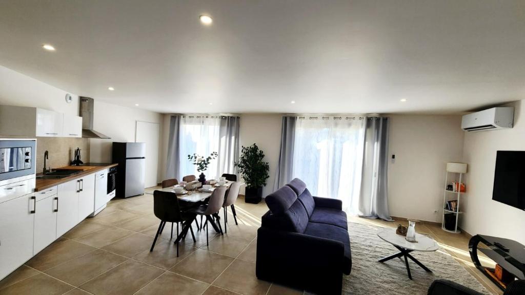 a kitchen and living room with a table and a couch at La maison des Vignes est climatisée avec ménage, draps et serviettes inclus in Tabanac
