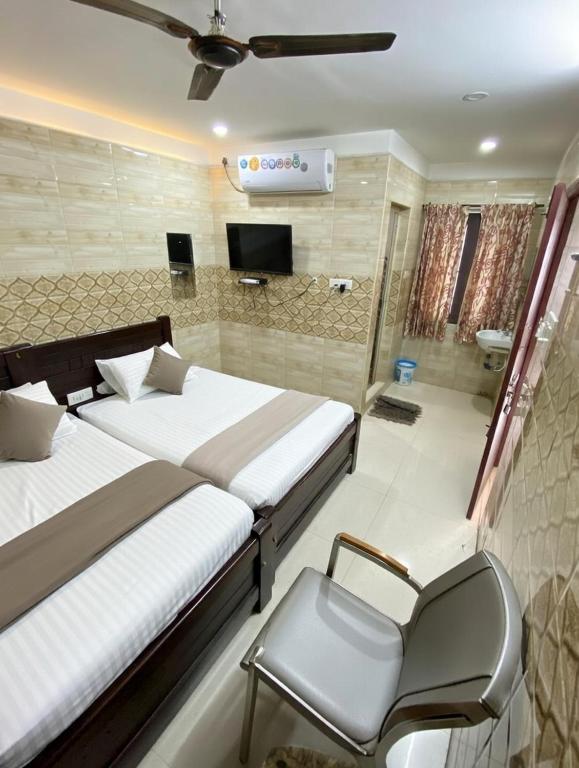 a bedroom with two beds and a chair in it at SAMPATH RESIDENCY in Palni