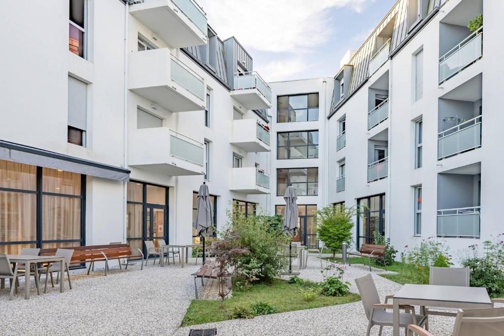 an apartment building with a courtyard with tables and chairs at Quality Aparthotel Rochefort in Rochefort