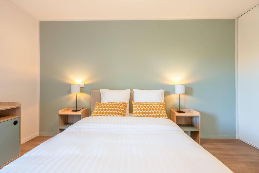 a bedroom with a large white bed with two lamps at Quality Aparthotel Moissy-Cramayel in Moissy-Cramayel
