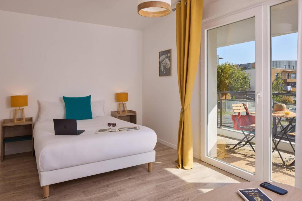 a bedroom with a bed with a laptop on it at Quality Aparthotel Orleans Sud Zenith in Olivet