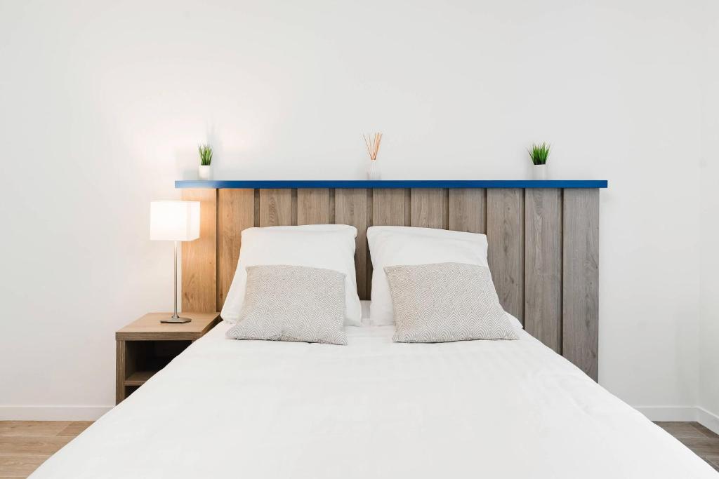 a bedroom with a white bed with a blue headboard at Quality Aparthotel Saint-Malo in Saint Malo