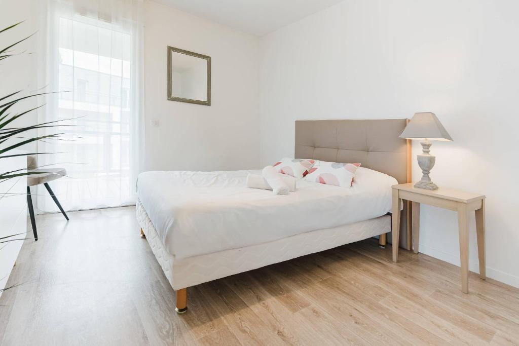 a white bedroom with a bed and a table at Quality Aparthotel St-Berthevin Laval in Saint-Berthevin-sur-Vicoin