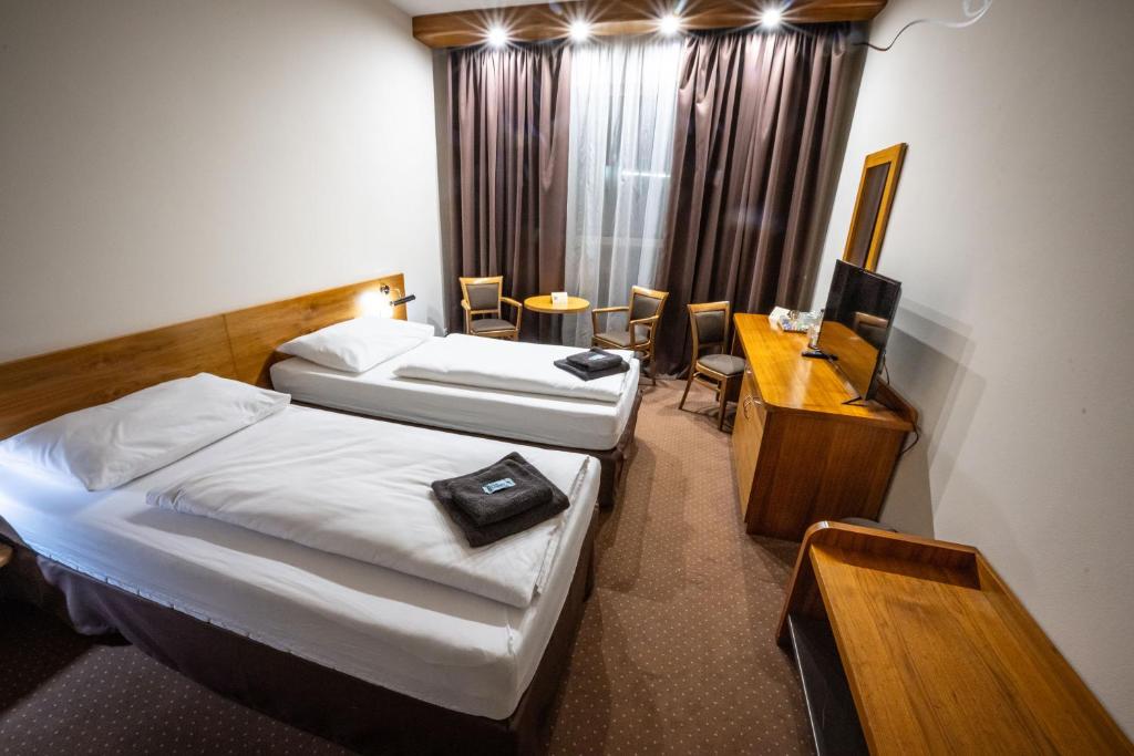 a hotel room with two beds and a desk at Hotel Opava - free parking in Opava
